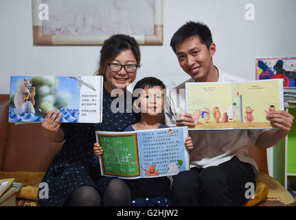 (160531) -- BEIJING, 31 mai 2016 (Xinhua) -- Chen Chuanlin avec son spectacle familial illustré les livres créés par lui-même à la maison à Beijing, capitale de Chine, le 28 mai 2016. Chen Chuanlin, 33 ans, est un groupe de papa qui a un garçon de 4 ans appelé Beibei à Beijing. Chen a créé près de 100 livres illustrés pour Beibei au cours des quatre dernières années, en utilisant des crayons au début jusqu'à maintenant avec les logiciels de l'ordinateur. Chen a examiné ses dessins comme une communication avec Beibei. Chen, un éditeur travaillant pour une agence de presse, a passé plus de temps dans ses temps libres à lire plus de livres et la création d'histoires intéressantes. Banque D'Images