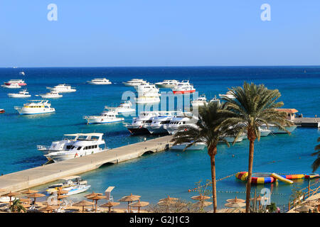 Yachts, et la plage avec parasols et chaises de détente dans un lieu de villégiature sur la mer Rouge à Hurghada, Egypte Banque D'Images