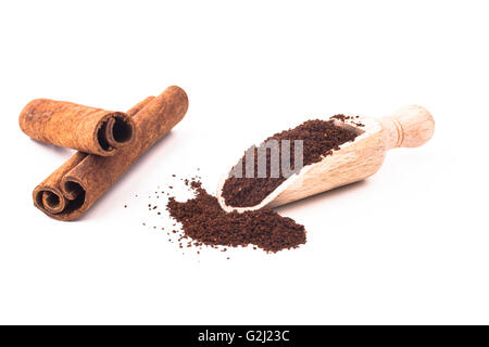 Café dans la cuillère en bois et des bâtons de cannelle isolé sur fond blanc Banque D'Images