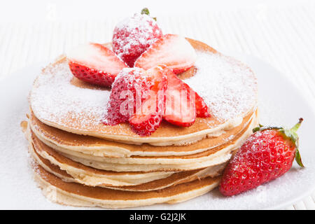 Des crêpes sur fond blanc avec sucre et fraise Banque D'Images