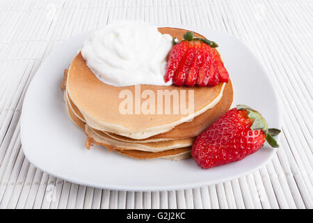 Des crêpes sur la plaque et l'arrière-plan blanc crème et fraise wiyh Banque D'Images