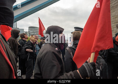 Groupe anarchiste du Premier Mai avec faces cachées, des slogans et des drapeaux rouges marchant sur le Tower Bridge 1er mai 2016 Banque D'Images