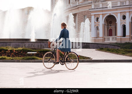 Pretty young woman riding a bike près de la fontaine dans la ville Banque D'Images