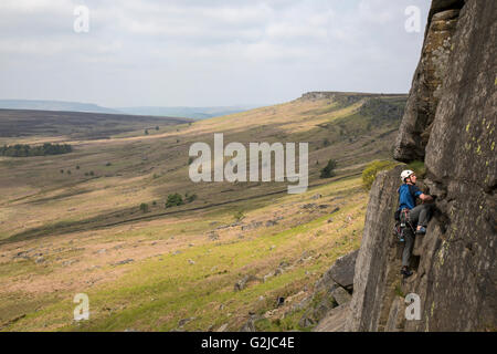 Grimpeur sur les falaises de Stanage Plantation dans le Peak District, Derbyshire, Angleterre. Banque D'Images