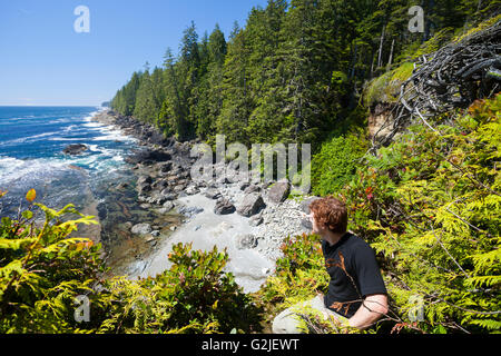 Un randonneur ressemble au nord d'une falaise le long du sentier de la côte ouest. La Réserve de parc national Pacific Rim, l'île de Vancouver, BC, Canada Banque D'Images