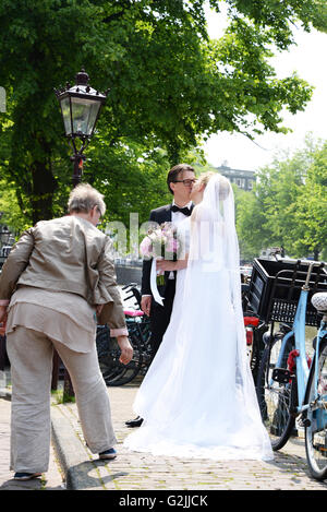 Meilleur contrôle de l'homme former couple nouvellement marié mariée avant de poser pour des photos sur pont sur un canal à Amsterdam. Banque D'Images