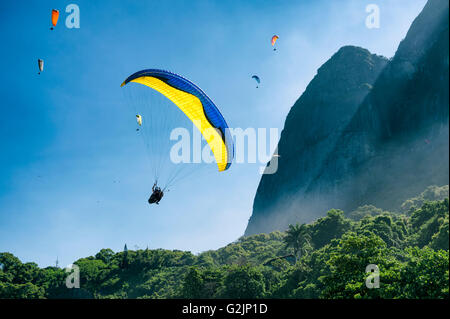 Parapentiste passe le long de la verdure de Misty Mountain Pedra da Gavea sur sa façon d'atterrir à São Conrado Beach à Rio de Janeiro Banque D'Images