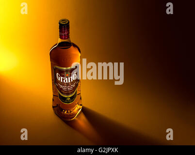 Bouteille de whisky Grant's sur un fond brun jaunâtre avec des reflets de lumière. Banque D'Images