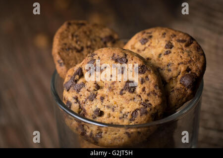 Close up of fresh baked cookies aux pépites de chocolat dans un verre sur une table en bois rustique. Banque D'Images