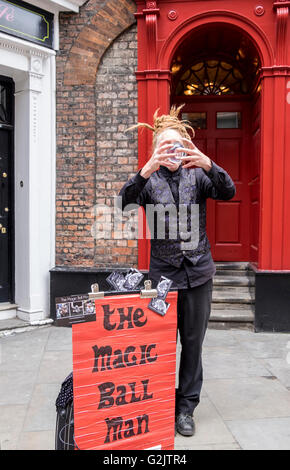 Artiste de rue de New York en Angleterre vêtus de noir l'exécution d'une magic ball Tour. Banque D'Images