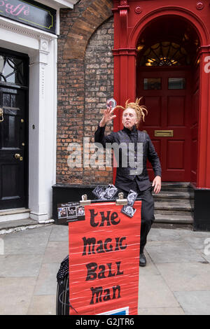 La boule magique homme soldes habilement sa boule de cristal sur le dos de sa main au cours d'une performance de rue à York, Angleterre Banque D'Images