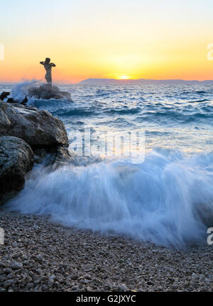 Statue de femme sur le rocher au coucher du soleil à Podgora, Riviera de Makarska, Croatie Banque D'Images