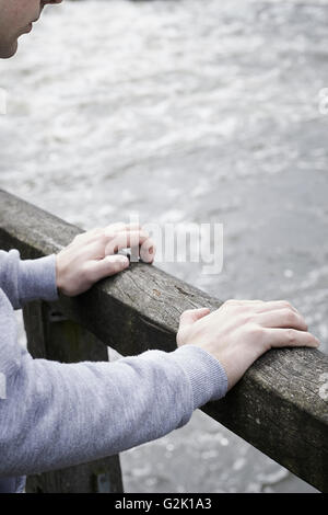 Jeune homme déprimé envisagent le suicide sur le pont sur la rivière Banque D'Images