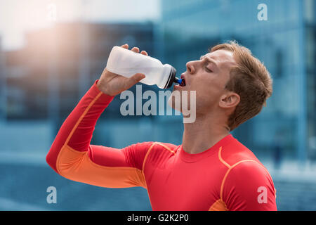 Sportif Sportif de boire de boisson énergétique. L'exécution de l'eau homme ville Banque D'Images