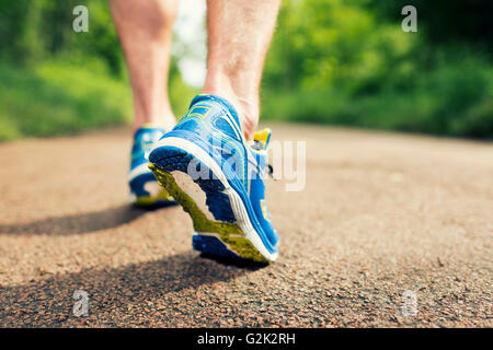 Libre de chaussures de course en action sur la route dans la forêt. Banque D'Images