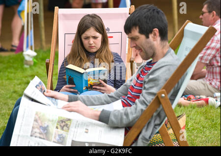 Les visiteurs la lecture de livres sur la pelouse à l'Hay Festival 2016 Banque D'Images