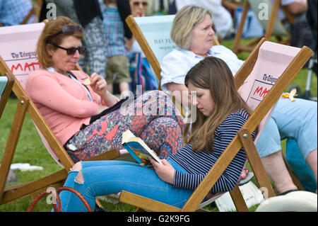 Les visiteurs la lecture de livres sur la pelouse à l'Hay Festival 2016 Banque D'Images