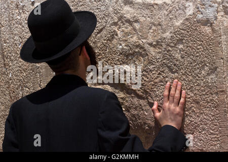 L'homme religieux juifs priant devant le mur occidental, une main sur le mur Banque D'Images