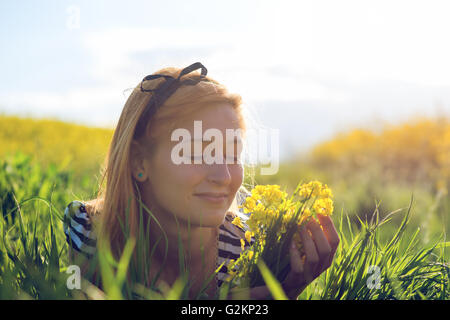 Cute young girl au milieu d'un champ de fleurs jaunes Banque D'Images