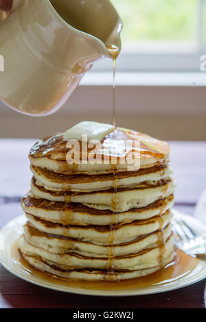 Le sirop est versé plus de pile de crêpes Banque D'Images