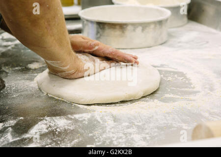 Les mains du boulanger la pâte d'aplatissement Banque D'Images