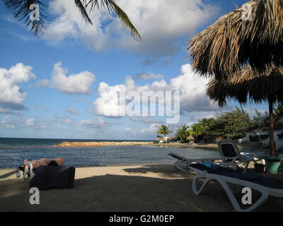 Beau Soleil, plage des Caraïbes chaud allumé sable doré et ciel dramatique, de l'hôtel Decameron, Runaway Bay, avec cocotiers Banque D'Images
