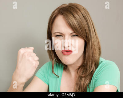 Portrait d'une colère mal trempé young caucasian woman froncer et secouant son poing à l'appareil photo Banque D'Images