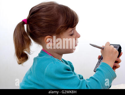 Petite fille jouant avec un stylo argent sur plmtop compter fond blanc Banque D'Images