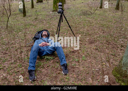 Photographe est allongé sur le sol près de l'appareil permanent et à la recherche dans la distance. Banque D'Images