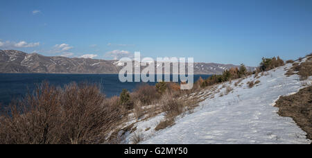 Vue panoramique sur le lac Sevan avec snow maintient autour de c Banque D'Images