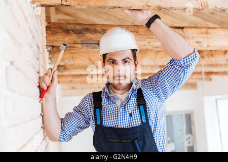 Close-up portrait of a handsome young builder holding a hammer Banque D'Images