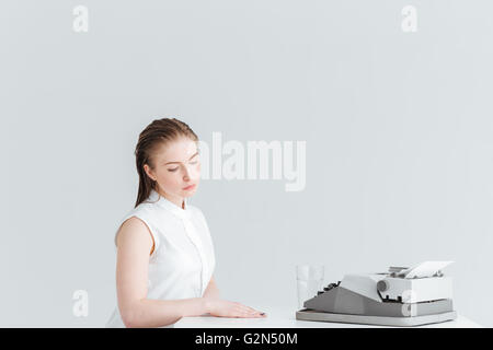 Relaxed woman assis à la table avec la machine rétro isolé sur fond blanc Banque D'Images