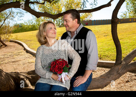Un couple célèbre son anniversaire. La femme tient un bouquet de rose pour symboliser son mariage fleurs. Banque D'Images