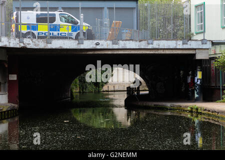 Métaphore de la sécurité de la rue : la police britannique véhicule et un cycliste non identifiés passant sous le pont sur le canal Bank à Londres Banque D'Images