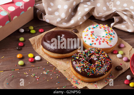 Beignes et bonbons sur table en bois Banque D'Images