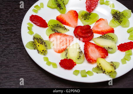 Tranches de kiwi et des fraises couché dans une manière ordonnée placée sur la plaque blanche, comme ci-dessus de Senn Banque D'Images