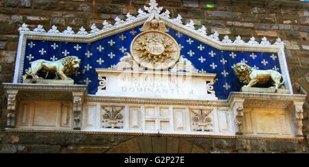 Détail de l'entrée avant le Palazzo Vecchio. Hôtel de ville de Florence, en Italie. Un immense palais-forteresse romane donnant sur la Piazza della Signoria. L'entrée présente une plante ornementale en frontispice, datant de 1528. Le monogramme du Christ se trouve au milieu, flanqué de deux lions dorés, avec le texte latin : 'Rex Regum et Dominus Dominantium". Ce qui peut être traduit comme : "par Jésus Christ, Roi des Rois et Seigneur des Seigneurs". Ce texte date de 1851. Banque D'Images