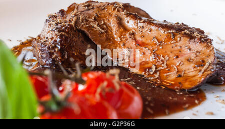 Délicieux à saignante, steak au poivre avec sauce aux herbes, tomates cerises, herbes et repas. Banque D'Images