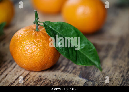 Mandarin Orange vif avec feuille verte sur planche de bois rustique Banque D'Images