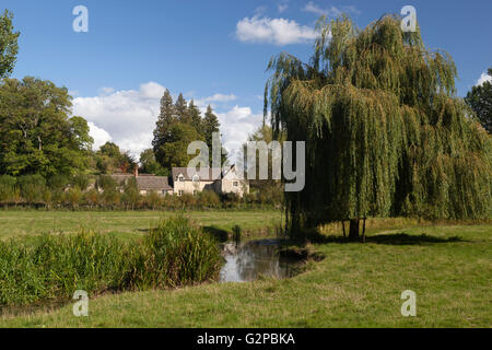 Cotswold cottage et willow tree au bord de la rivière Coln St Aldwyns, Coln, Cotswolds, Gloucestershire, Angleterre, Royaume-Uni, Europe Banque D'Images