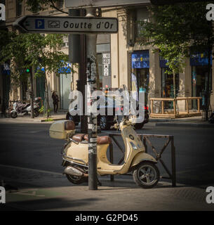 Scooter jaune garée sur un trottoir dans une rue de Paris Banque D'Images