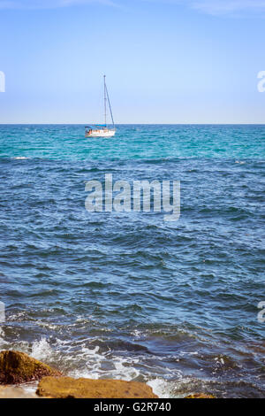 Voilier flottant dans la mer sur la côte, l'horizon de Sunny Beach, Av de los Marineros, Torrevieja, Communauté Valencienne, Espagne Banque D'Images