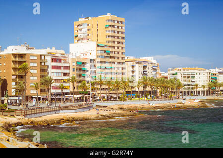 Plage méditerranéenne ensoleillée, les touristes se détendre par beau rivage de mer sur des chaises longues sous les parasols. Les gens se baignent dans l'eau cristalline Banque D'Images