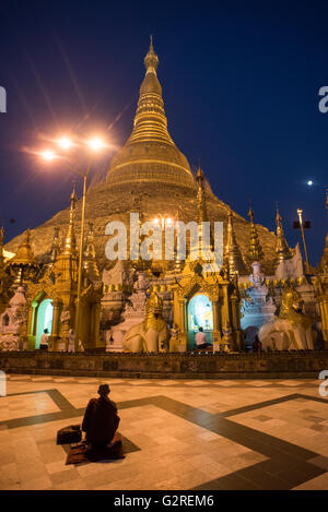 Un moine bouddhiste prie en face de la pagode Shwedagon à Yangon, Myanmar. Banque D'Images