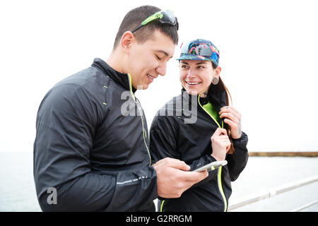 Happy young couple using smartphone et talking outdoors Banque D'Images