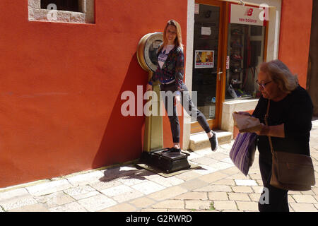 Une jeune fille cherche son poids sur une ancienne machine de pesage dans une rue à Zadar, Croatie Banque D'Images