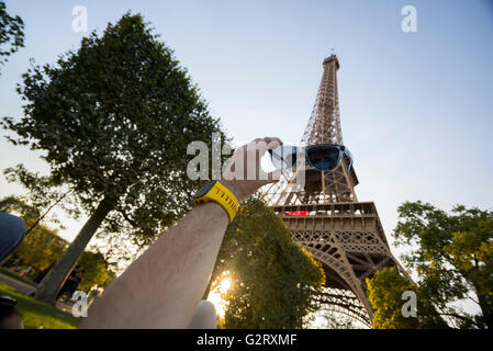 La Tour Eiffel vue d'en bas et une main tenant des parasols ce qui semble comme si la tour avait sur eux, Paris, France. Banque D'Images