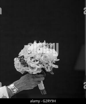 Bouquet de fleurs fraîches coupées en noir et blanc qui s'est tenue à une main de femme avec un fond noir Banque D'Images