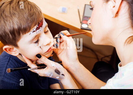 Mignon petit enfant faisant facepaint sur anniversaire, Apocalypse zombie, halloween concept préparation facepainting Banque D'Images