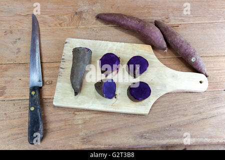 Violet à la vapeur les patates douces pommes de terre crues et split sur bois Banque D'Images